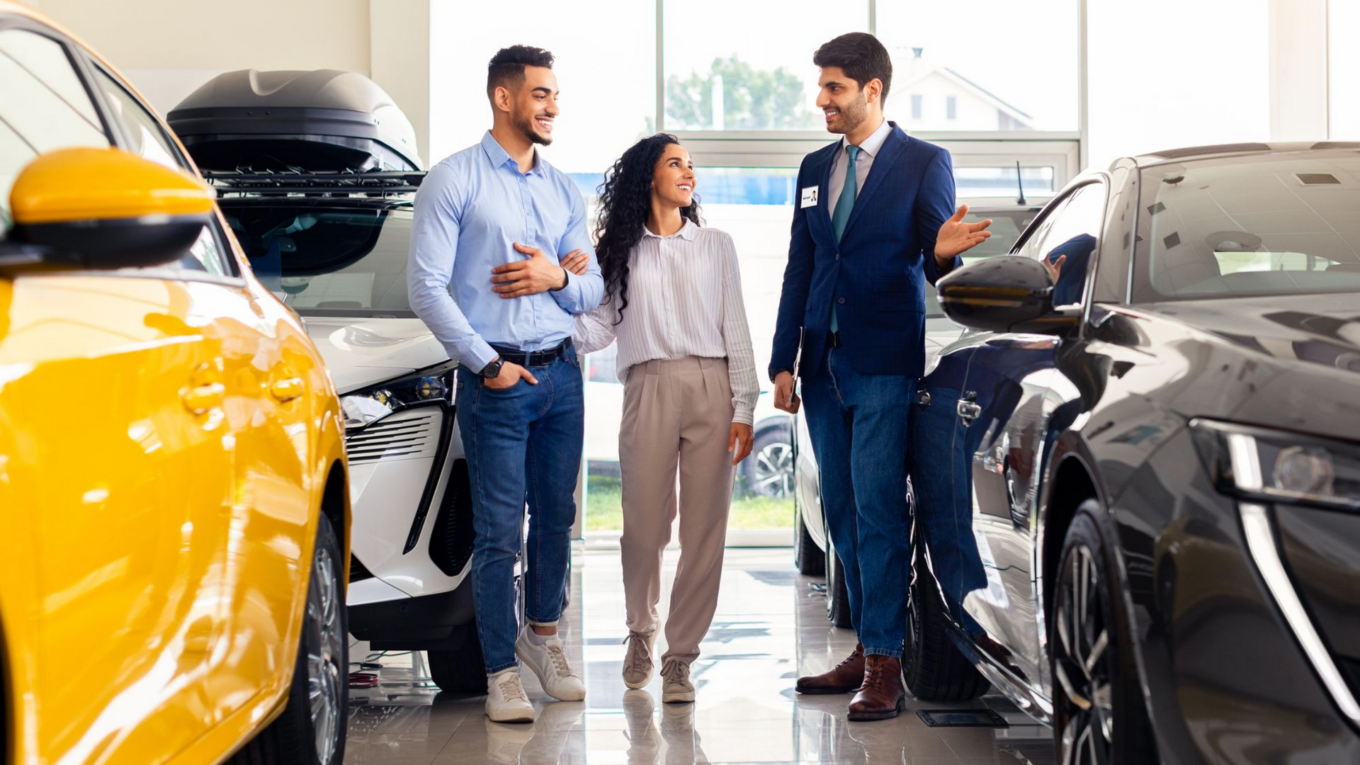 Vendeur présentant des voitures à vendre à un jeune couple