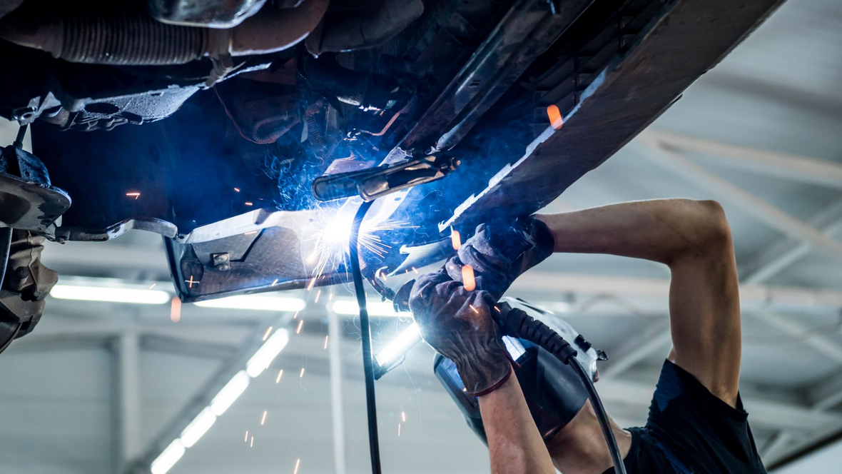 Mécanicien soudant une pièce auto