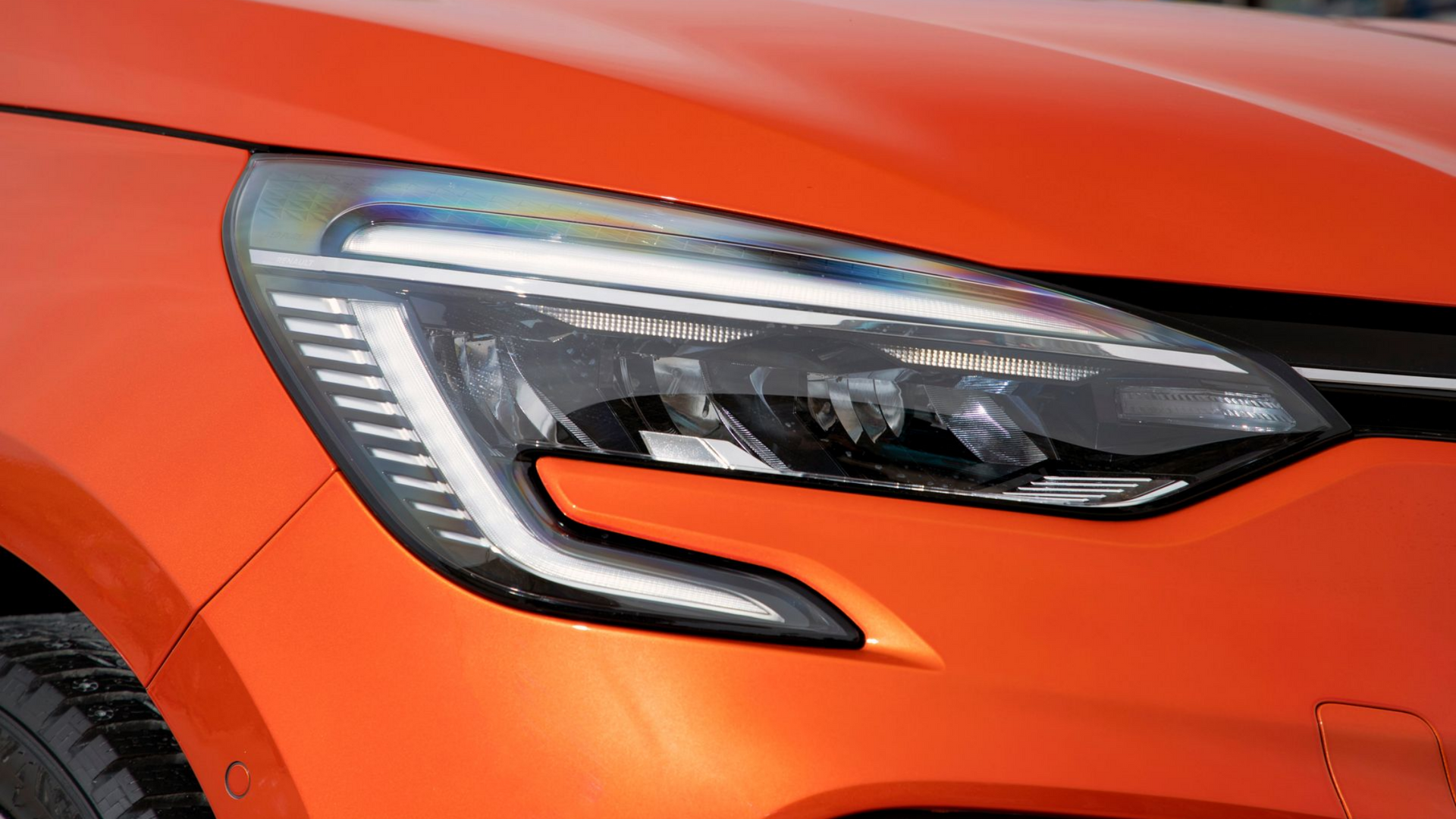 Gros plan sur le phare avant d'une Clio orange