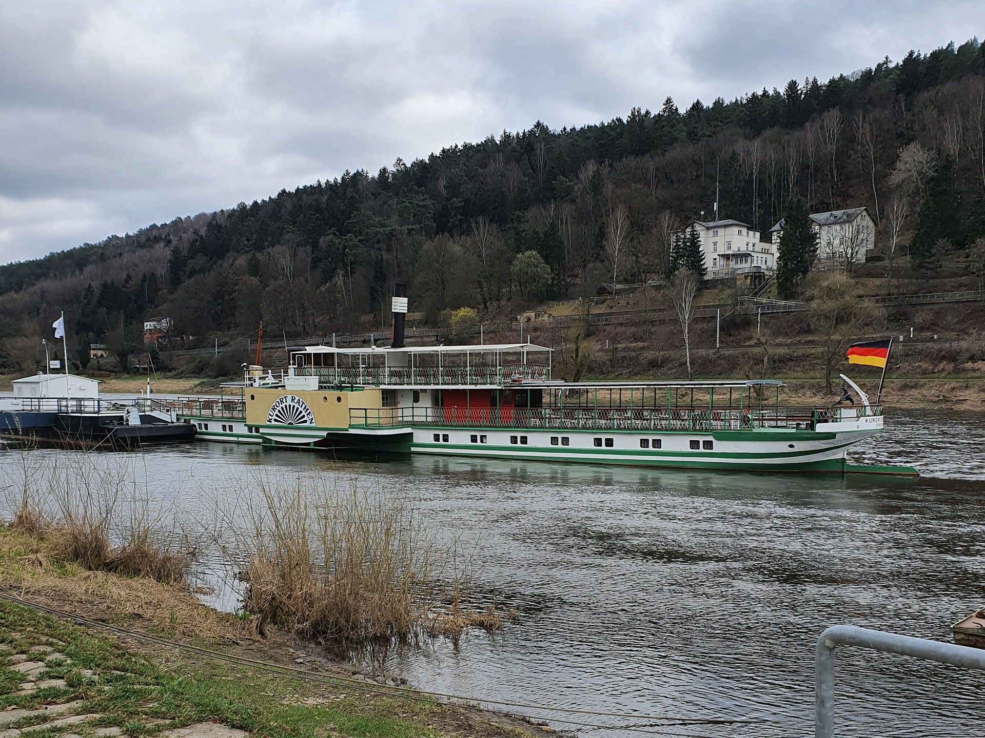 ein weiß-grünes Boot fährt auf einem Fluss