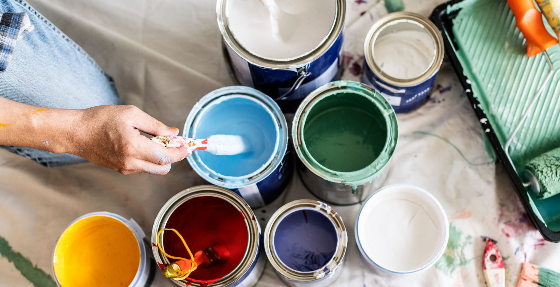 Une personne qui tient le pinceau au-dessus des pots de peinture.