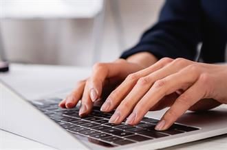 Hände tippen auf einer Laptoptastatur und konzentrieren sich auf die Arbeit; drinnen.