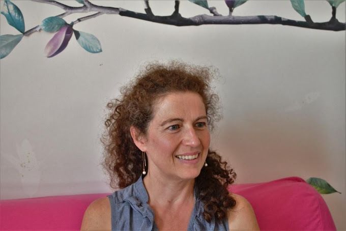 Portrait de Sandrine Taisne sur un canapé rose
