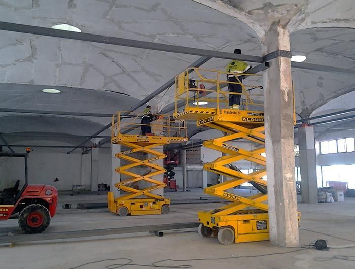 Un hombre está de pie sobre un elevador de tijera en un almacén.