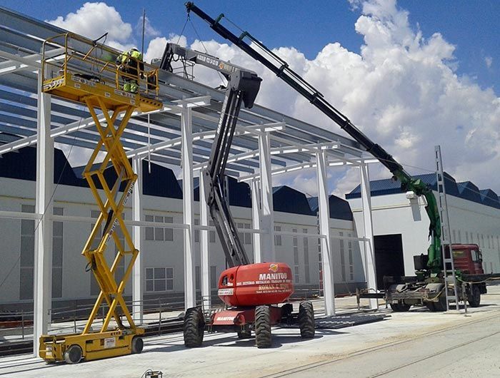 Un hombre en un elevador de tijera está trabajando en un edificio.