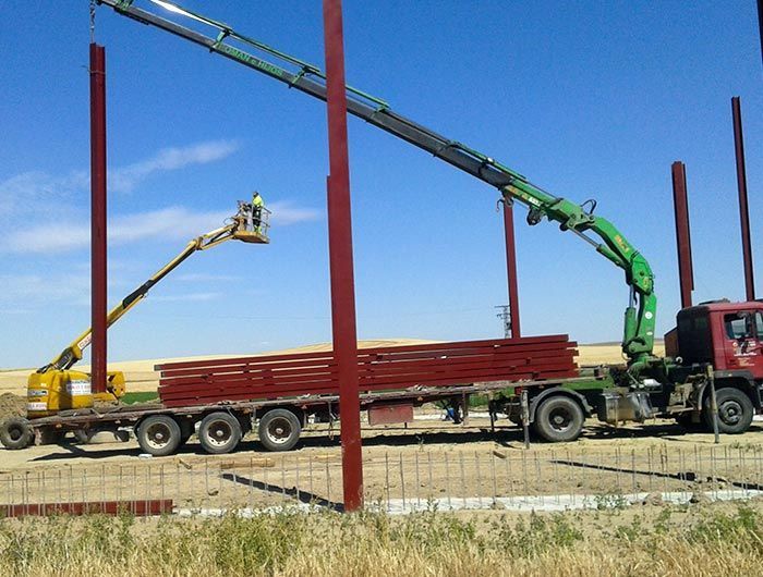 Un camión rojo con una grúa verde acoplada.