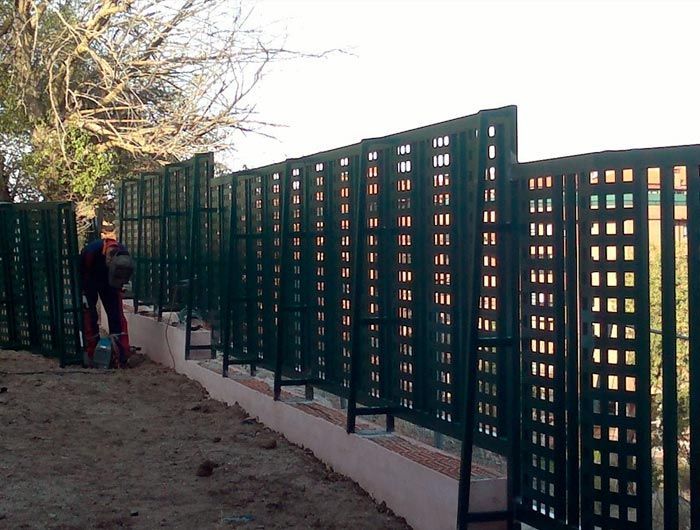 Un hombre está trabajando en una valla que tiene agujeros.