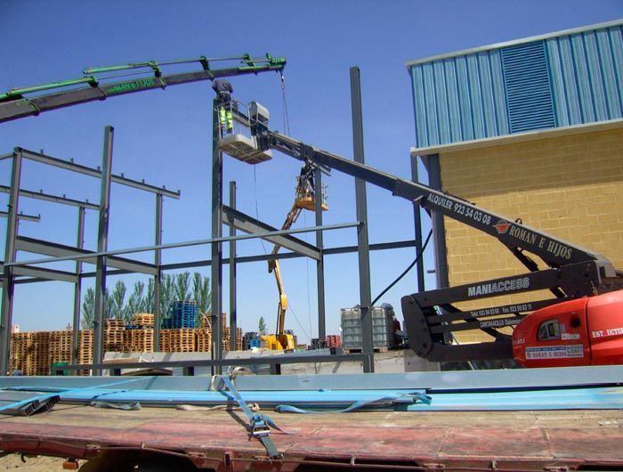 Una grúa está levantando una estructura metálica frente a un edificio.
