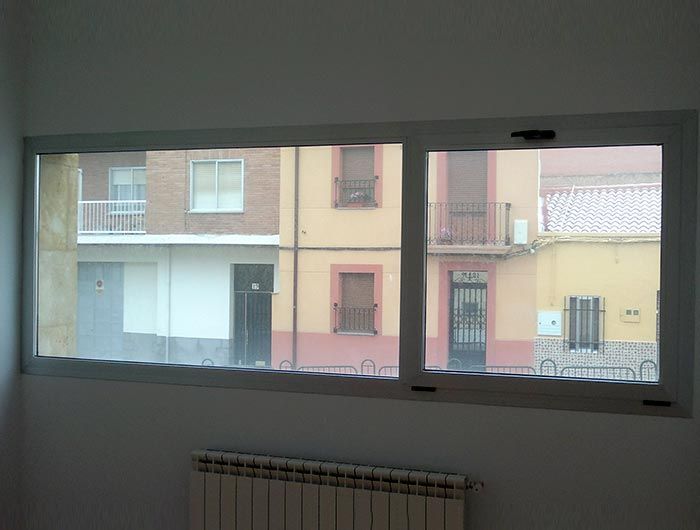 Una habitación con radiador y ventana con vistas a los edificios.