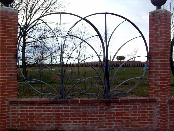 Una pared de ladrillos con una puerta de hierro forjado en el medio.