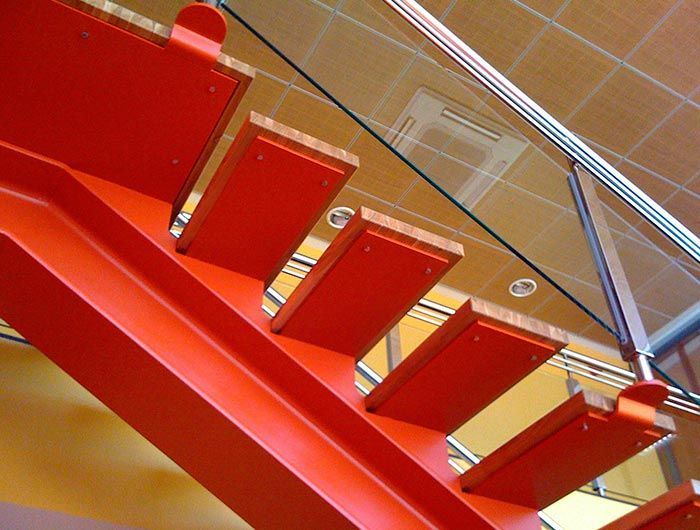 Una escalera roja con barandilla de cristal transparente.