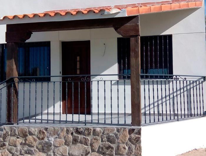 Una casa blanca con un balcón y un muro de piedra.