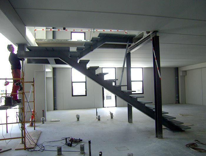 Un hombre de pie en un andamio al lado de una escalera.