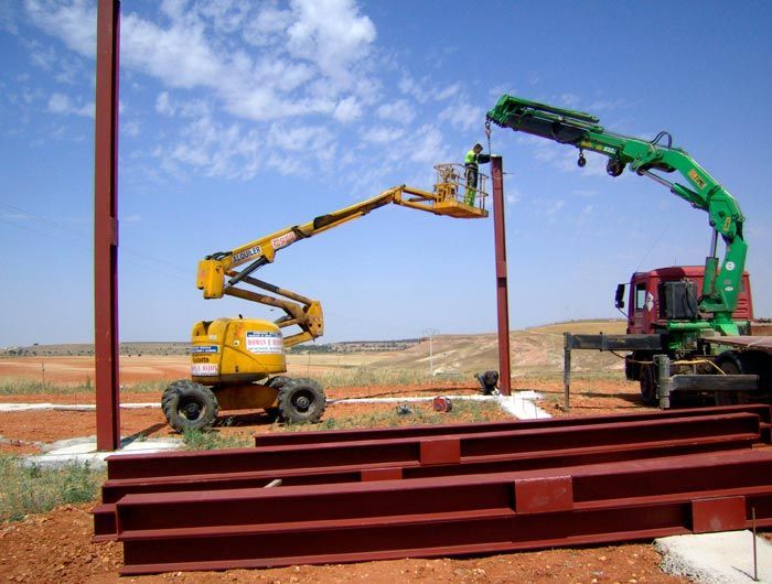 Una obra en construcción con una grúa y un elevador amarillo.