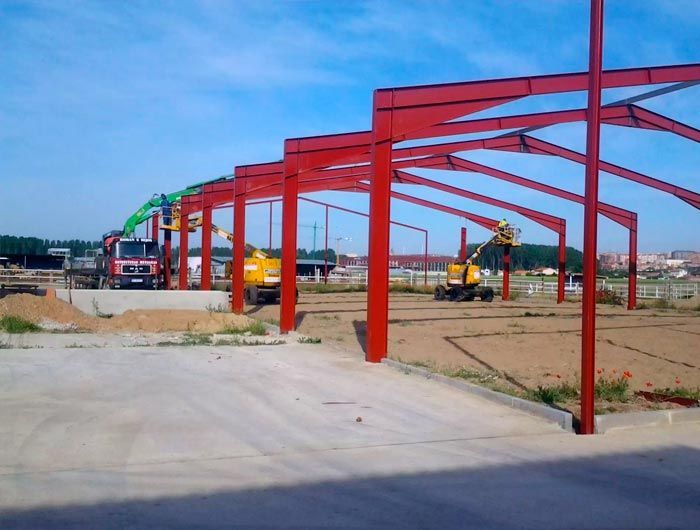 Se está construyendo una hilera de estructuras metálicas rojas en un estacionamiento.