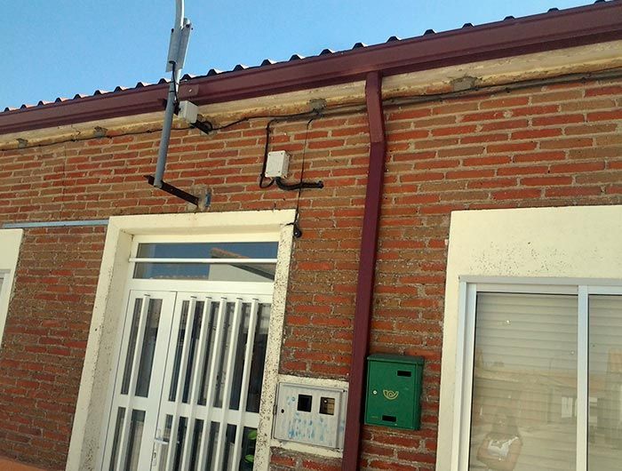 Un edificio de ladrillos con un buzón verde en el costado.