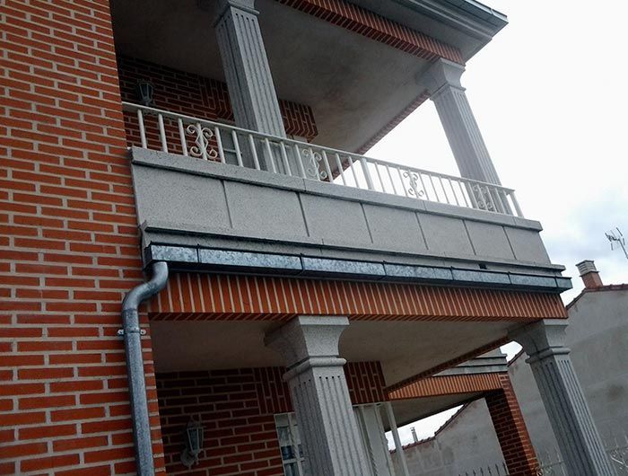 Un edificio de ladrillo con un balcón y una canaleta.