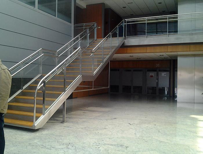 Una escalera en un edificio con barandilla de acero inoxidable.