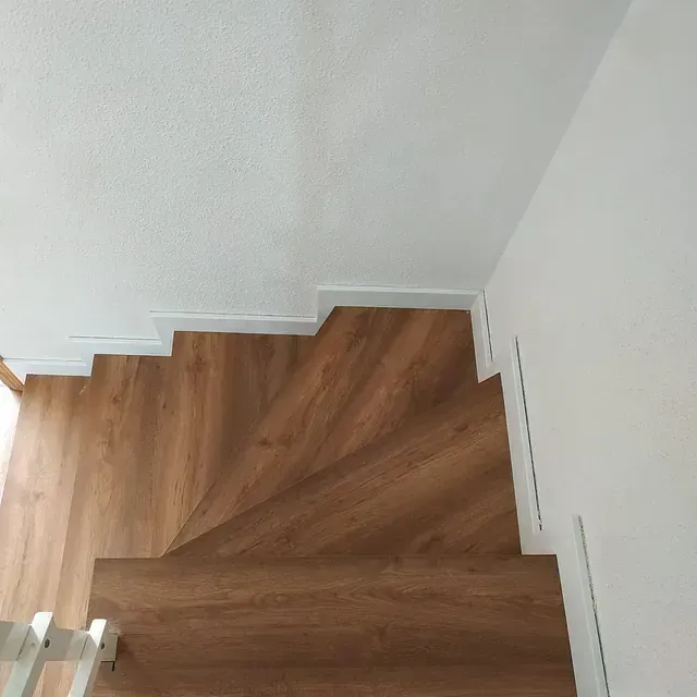 Las escaleras son de madera y tienen barandilla blanca.