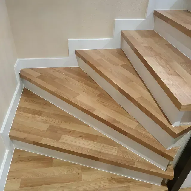 Una escalera con escalones de madera y molduras blancas.