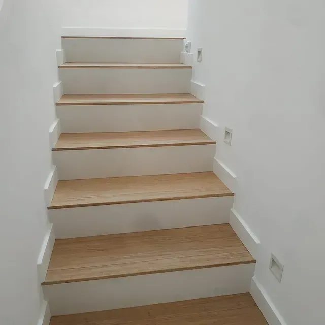 Un conjunto de escaleras con escalones de madera y paredes blancas.