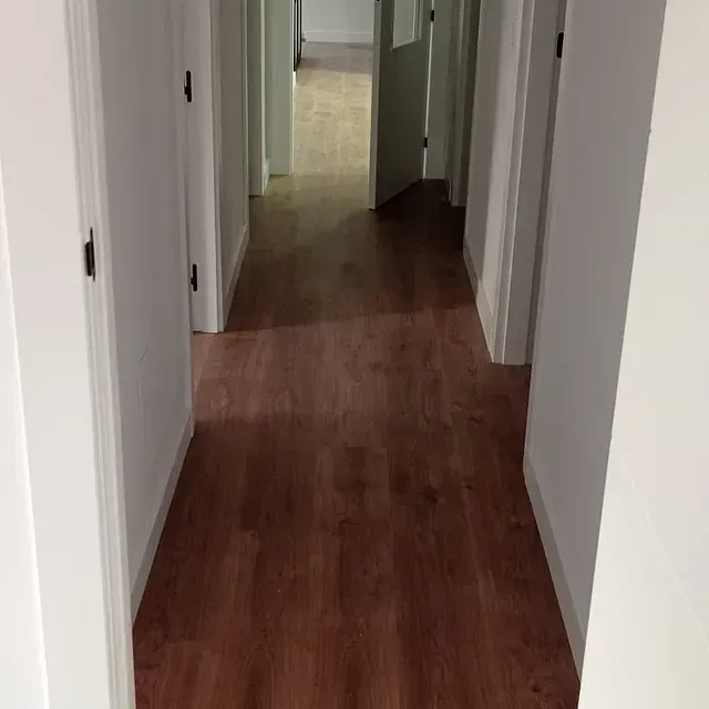 Un pasillo con suelos de madera y paredes blancas en una casa.