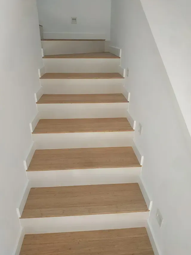 Un conjunto de escaleras con escalones de madera y paredes blancas.