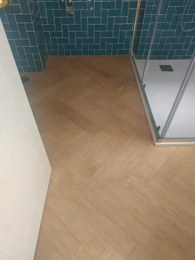 Un baño con suelo de madera y cabina de ducha.