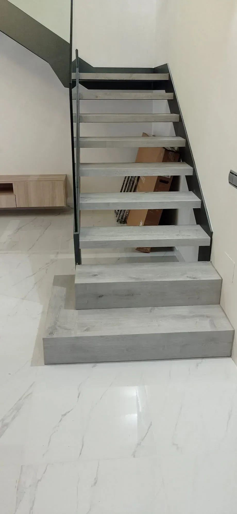 Una escalera con escalones de mármol y barandilla de metal en una habitación.