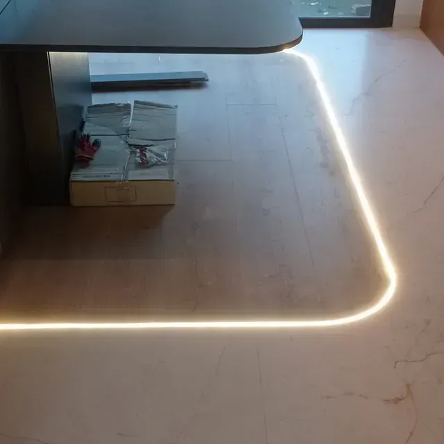 Un rincón de un piso de madera con una luz que sale de él.