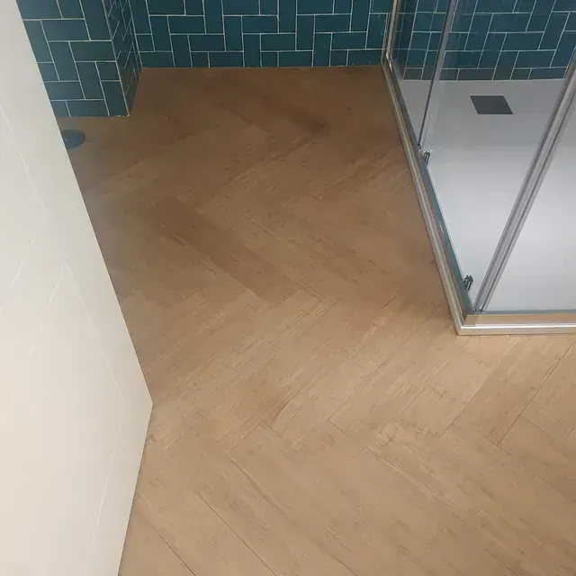 Un baño con suelo de madera y cabina de ducha.