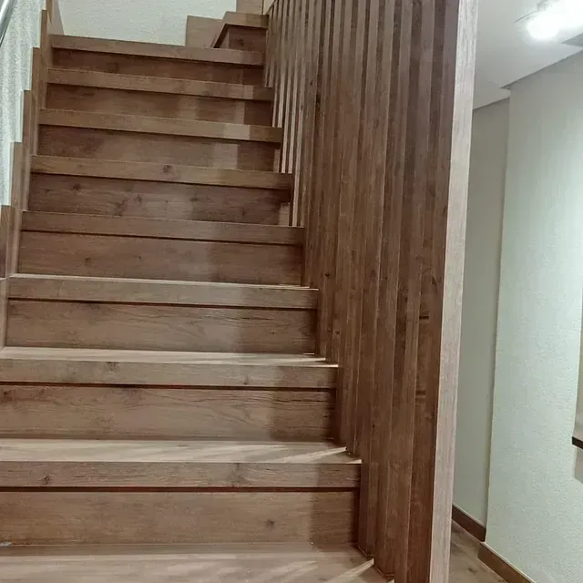 Una escalera de madera con barandilla de madera en un pasillo.