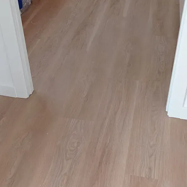 Un primer plano de un piso de madera en una habitación al lado de una puerta.