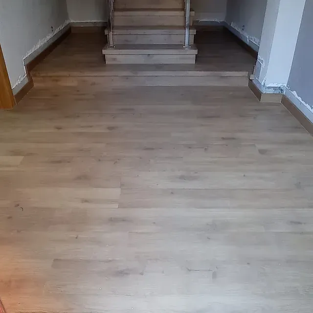 Un piso de madera con escaleras al fondo en una habitación.