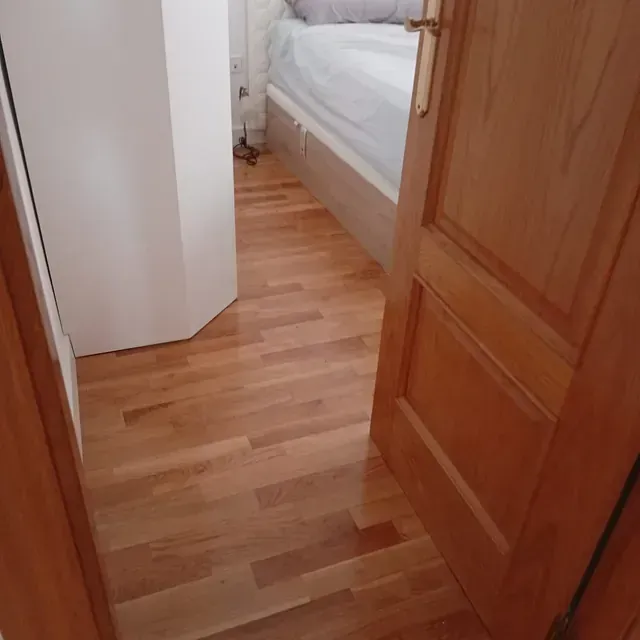 Un dormitorio con suelo de madera y una cama.