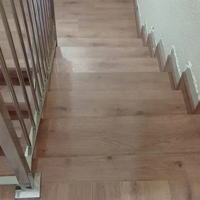 Un primer plano de una escalera de madera con barandilla de metal.
