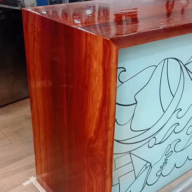 Una mesa de madera con borde de vidrio tiene un dibujo de un barco.