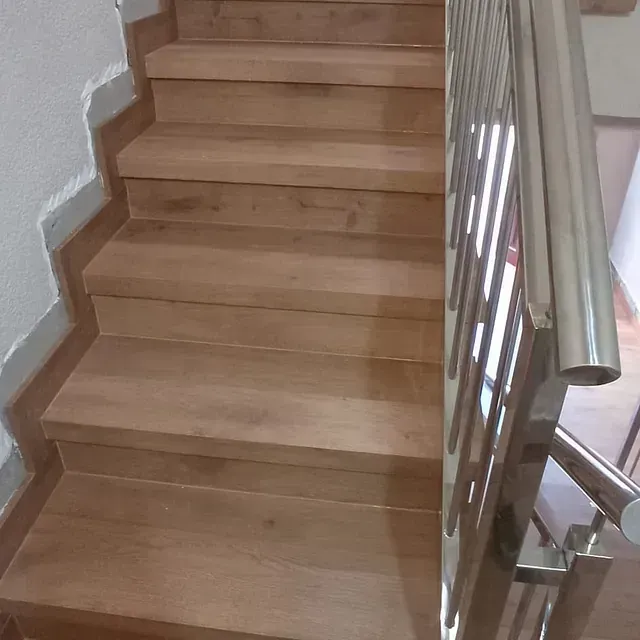 Una escalera de madera con barandilla de metal en una casa.