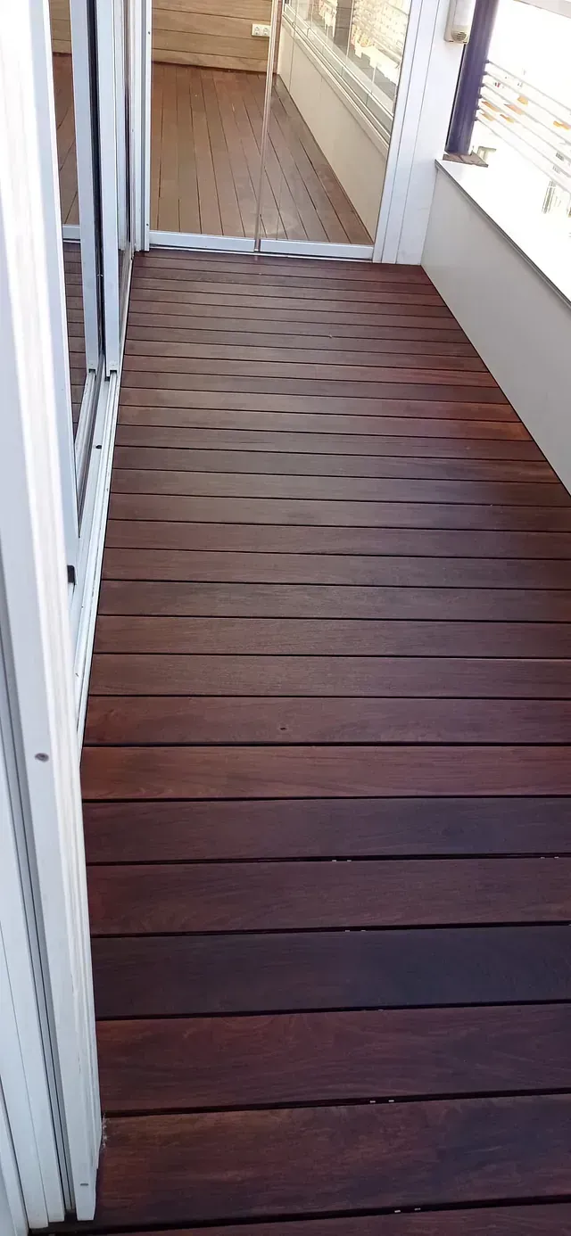 Una pasarela de madera que conduce a un balcón con terraza de madera.
