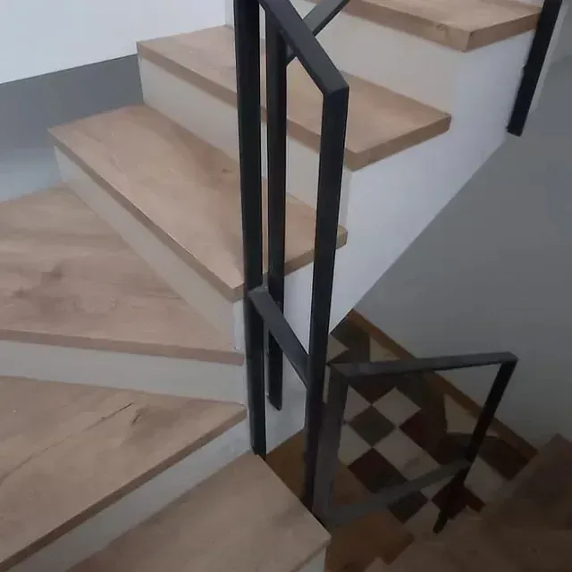 Una escalera con escalones de madera y barandilla negra.