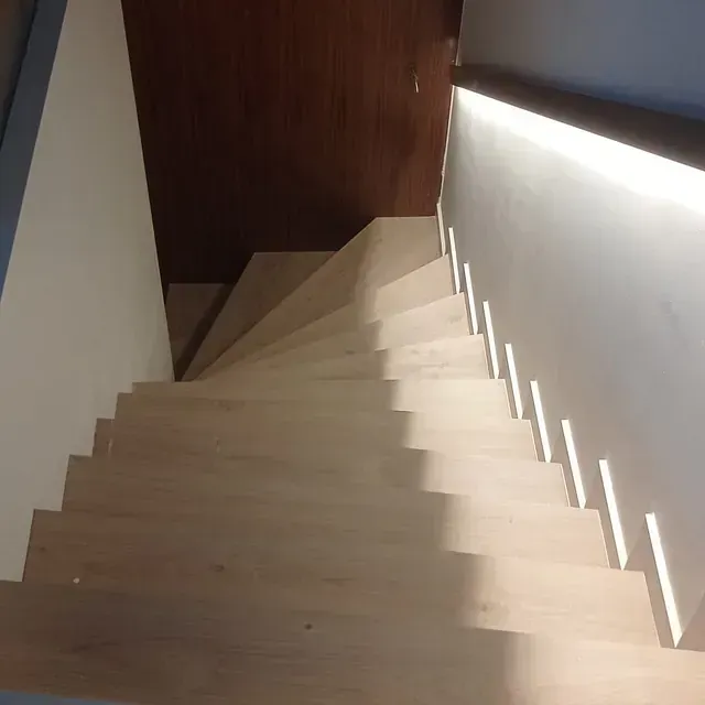 Una escalera de madera con una luz en la barandilla.