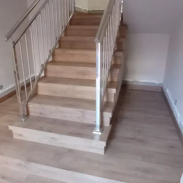 Una escalera de madera con barandilla de metal en una habitación.