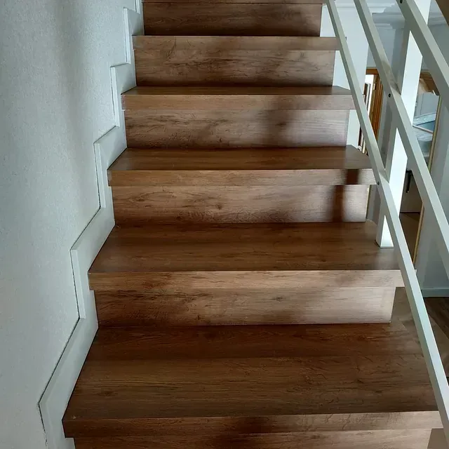 Las escaleras son de madera y tienen barandilla blanca.