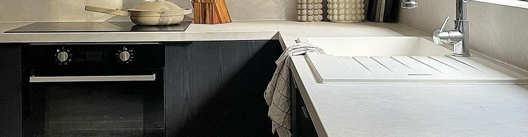 Une cuisine moderne avec un four noir et un plan de travail clair avec un évier.