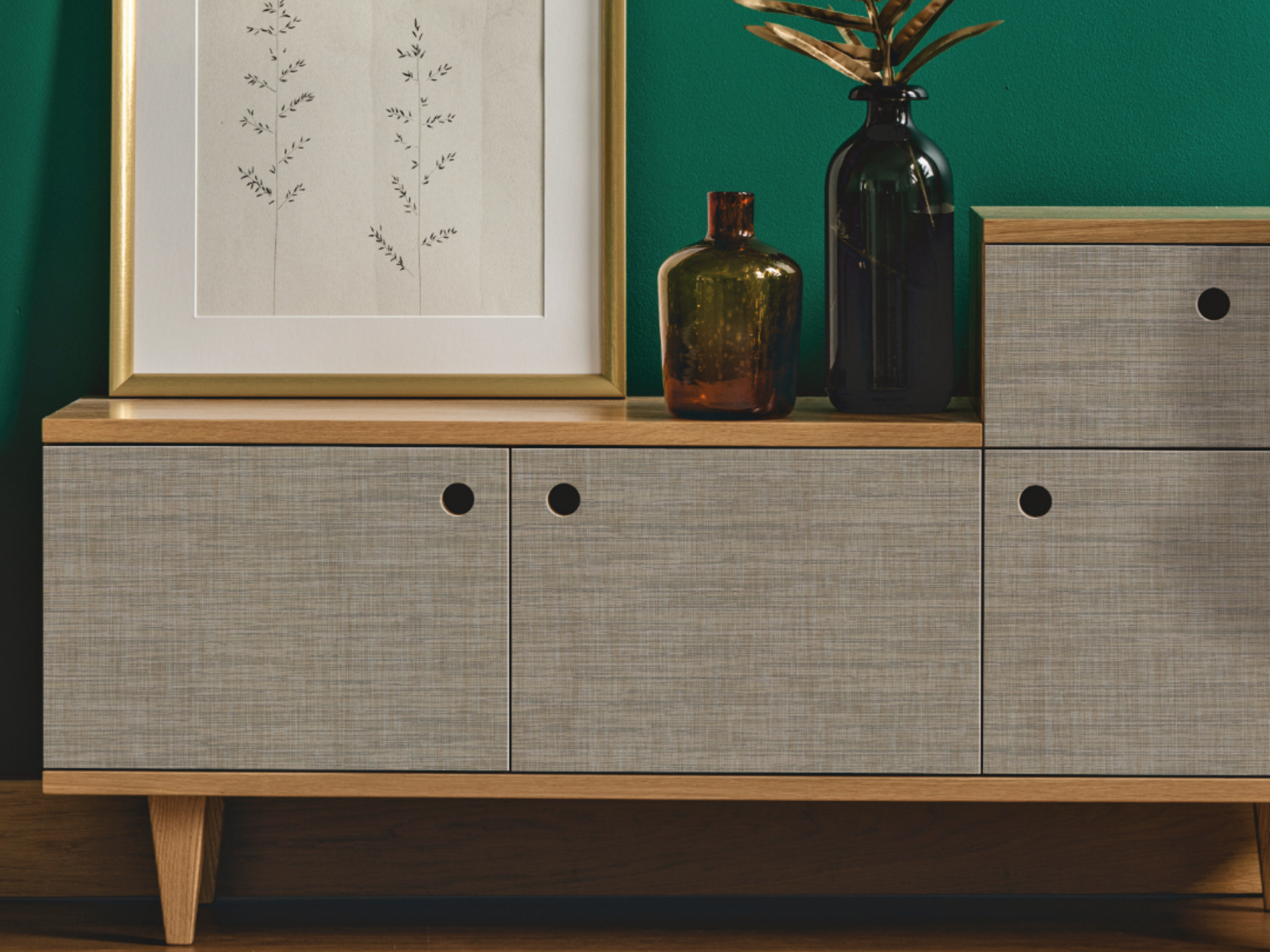 Buffet en bois avec portes recouvertes d'adhésifs décoratifs, orné d'objets décoratifs et d'œuvres d'art, devant un mur vert.