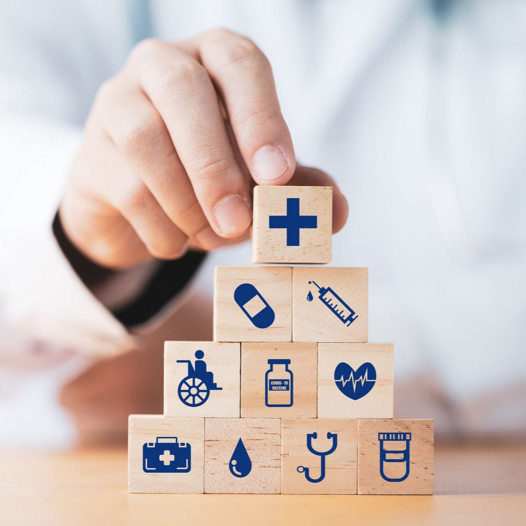 Une main empile des cubes avec des pictogrammes médicaux