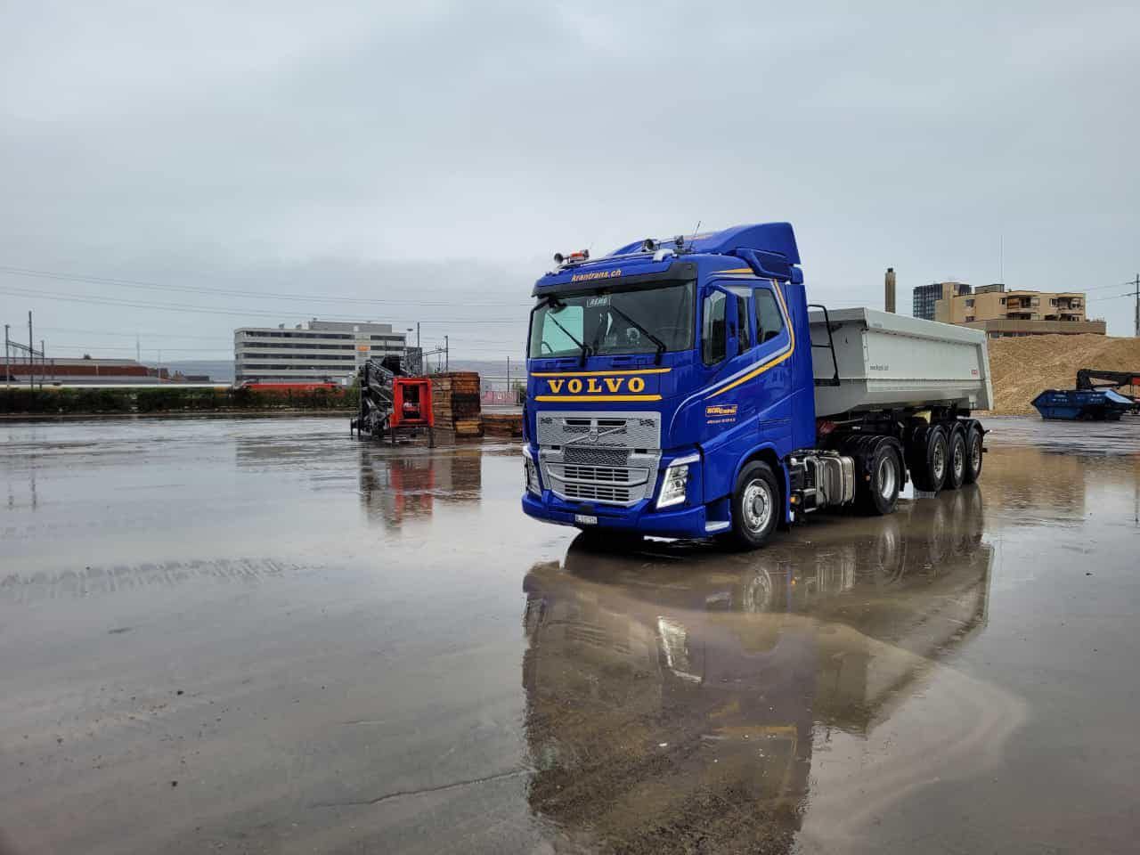 ein blauer Volvo-Lkw fährt auf einem nassen Parkplatz