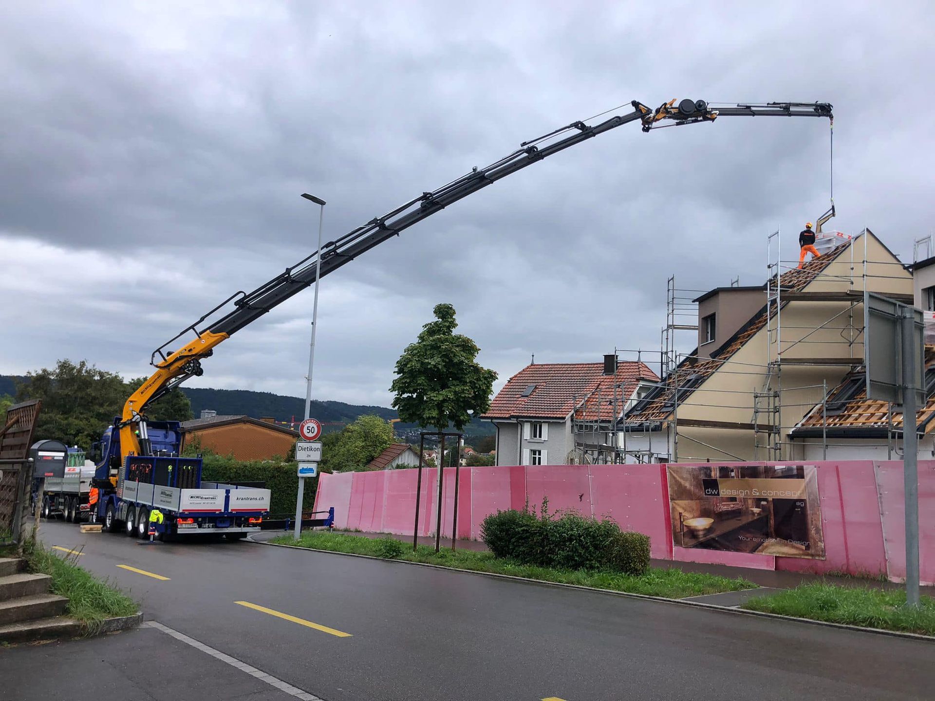 ein Kran trägt einen Anhänger mit einem Schild darauf