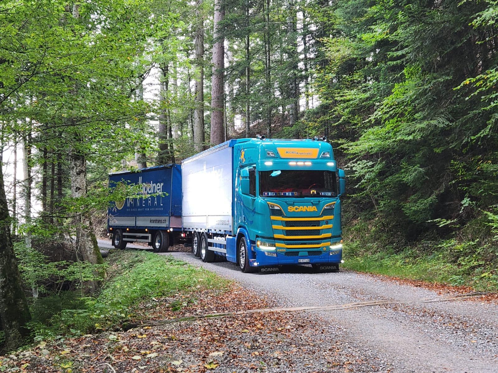 ein blauer Scania-Lkw fährt auf einer unbefestigten Straße
