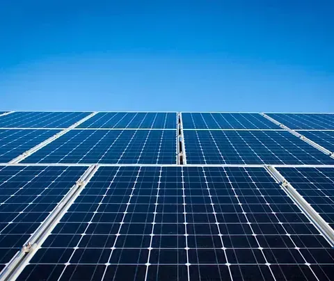 Persona señalando el plano de una casa con un panel solar y una tabla de colores sobre la mesa.